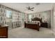 Bright main bedroom featuring a dark wood bed frame, patterned curtains, and a ceiling fan at 9747 W Sands Dr, Peoria, AZ 85383