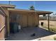 Backyard concrete patio with covered area, large trash bin and door entrance at 1039 E Broadway Rd, Mesa, AZ 85204