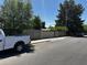 View of the fenced property from the street, featuring mature trees and a glimpse of the neighborhood at 1039 E Broadway Rd, Mesa, AZ 85204