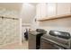 This laundry room includes side-by-side, front-load machines and ample storage at 10822 W Quail Ave, Peoria, AZ 85373