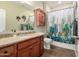 Well-lit bathroom with warm color scheme, granite vanity, decorative mirror and cactus themed shower curtain at 13123 W Cottontail Ln, Peoria, AZ 85383