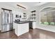 Well-lit kitchen with a center island, stainless steel appliances, white cabinetry, open wood shelving and a window at 1350 S Greenfield Rd # 1166, Mesa, AZ 85206