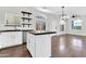 Kitchen island with black countertops, a stainless sink, open shelves, and views of living area at 1350 S Greenfield Rd # 1166, Mesa, AZ 85206