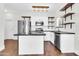 Bright kitchen with modern stainless steel appliances, white cabinets, floating shelves, and a black countertop island at 1350 S Greenfield Rd # 1166, Mesa, AZ 85206