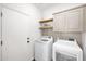 Functional laundry room with front loading washer and dryer, and overhead cabinets at 1462 E Sweet Citrus Dr, Queen Creek, AZ 85140