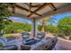 Covered patio with cushioned seating, fire pit, and landscaped backyard at 1462 E Sweet Citrus Dr, Queen Creek, AZ 85140