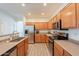 Well-lit kitchen featuring modern stainless steel appliances, wood cabinetry, and easy-to-clean flooring at 1851 E Ellis St, Phoenix, AZ 85042