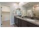 Bright ensuite double vanity with bronze fixtures, granite countertop, walk-in closet, and walk-in shower at 20644 W Mariposa St, Buckeye, AZ 85396