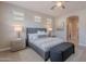 Well-lit main bedroom featuring gray upholstered headboard, bedside tables, and doorway to the ensuite at 20644 W Mariposa St, Buckeye, AZ 85396