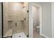 Tiled shower with glass door featuring a bench and dark hardware alongside a toilet in the adjacent room at 20644 W Mariposa St, Buckeye, AZ 85396