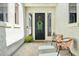 Inviting front porch with a stylish black door, decorative wreath, and cozy seating, offering a warm welcome to guests at 21391 W Mariposa St, Buckeye, AZ 85396