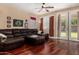 Spacious living room featuring a plush brown leather sofa, ceiling fan, and bright natural light from the doors to outside at 3065 E Harvard Ave, Gilbert, AZ 85234