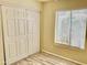 Bedroom showcasing a double sliding door closet, window with blinds, and wood-look vinyl flooring at 3121 W Laurie Ln, Phoenix, AZ 85051