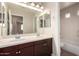 Bathroom featuring double sinks, large mirror, wood vanity, and a combined tub and shower at 3449 E Sheffield Rd, Gilbert, AZ 85296