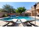 A luxurious backyard oasis featuring a sparkling pool with a waterfall feature and lounge chairs at 3693 E Sparrow Pl, Chandler, AZ 85286