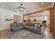Bright living room featuring a large gray couch, wooden beams, and an open floor plan leading into the kitchen at 3931 E Weather Vane Rd, Gilbert, AZ 85296