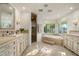 Bright bathroom with double sinks, travertine-like tile, large mirror and a separate shower and tub at 5112 N 41St St, Phoenix, AZ 85018