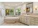 Bright bathroom features an oval soaking tub, tiled floors and a large picture window with a backyard view at 5112 N 41St St, Phoenix, AZ 85018