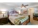Well-lit bedroom with a ceiling fan, artwork, and a plush bed featuring a decorative wooden headboard at 5758 E Fox St, Mesa, AZ 85205