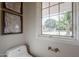 A white toilet in a bathroom sits near a window and modern artwork at 6525 N 3Rd St, Phoenix, AZ 85012