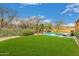 Large backyard featuring a sparkling pool, lush green lawn, and desert landscaping at 8298 E Tailfeather Dr, Scottsdale, AZ 85255