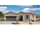 Charming single-story home featuring a stone facade, a two-car garage, and a well-manicured desert landscape at 8552 N 175Th Ln, Waddell, AZ 85355