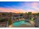 Sunset aerial view of a private pool with a spa, rock waterfall feature, and well-manicured landscaping at 8776 E Brilliant Sky Cir, Gold Canyon, AZ 85118