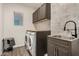Well-lit laundry room featuring stainless steel appliances, gray cabinets, and neutral tile backsplash at 11541 E Corbin Ave, Mesa, AZ 85212