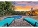 Backyard view with pool, lounge chairs, manicured landscaping, and sunset views at 11822 S Coconino St, Phoenix, AZ 85044