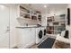 Bright laundry room with built-in shelving, ample storage, sink, folding area, and modern appliances at 11822 S Coconino St, Phoenix, AZ 85044