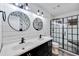 Well-lit bathroom featuring a double vanity, modern fixtures, and a glass-enclosed shower at 13207 N 55Th Ave, Glendale, AZ 85304