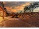 Backyard features a sparkling pool, lush landscaping, and rock accents under a stunning sunset sky at 14056 E Desert Cove Ave, Scottsdale, AZ 85259