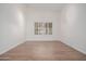 Bright, empty bedroom with wood-look tile flooring, a window with white blinds, and neutral paint at 14056 E Desert Cove Ave, Scottsdale, AZ 85259