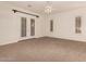 Bright bedroom features neutral carpet, ceiling fan, and shuttered doors to the outside at 14056 E Desert Cove Ave, Scottsdale, AZ 85259