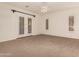 Bright bedroom features plush carpeting, ceiling fan, and access to the outdoors with shuttered windows at 14056 E Desert Cove Ave, Scottsdale, AZ 85259