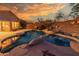 A luxurious pool with a rock waterfall feature, surrounded by desert landscaping, creates a serene outdoor escape at 14056 E Desert Cove Ave, Scottsdale, AZ 85259