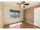 This bedroom has wood floors, a ceiling fan, and a large window providing natural light and neighborhood views at 16823 S 24Th Pl, Phoenix, AZ 85048