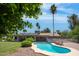 Scenic backyard with a shimmering pool, verdant lawn, mature palm trees, and a charming patio area at 18428 N 42Nd St, Phoenix, AZ 85032