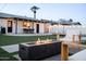 Cozy backyard featuring a modern fire pit, outdoor seating, and a well-manicured lawn with string lights at 2023 N 79Th Pl, Scottsdale, AZ 85257