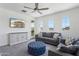 Bright upstairs bonus room with a gray sofa, tufted ottoman, ceiling fan and natural light from the windows at 22306 N 34Th Pl, Phoenix, AZ 85050
