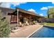 A covered patio with chairs sits to the side of the home's pristine pool and verdant landscaping at 25232 N Horseshoe Trl, Scottsdale, AZ 85255