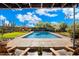 A beautiful in-ground swimming pool surrounded by mature landscaping and a lounging area under a wooden awning at 25232 N Horseshoe Trl, Scottsdale, AZ 85255