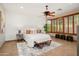 A spacious bedroom featuring a king-sized bed, a ceiling fan and a bay window with wooden shutters at 27581 N 129Th Ln, Peoria, AZ 85383