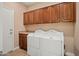 A well-organized laundry room with upper cabinets, tile flooring, and a white washer and dryer at 27581 N 129Th Ln, Peoria, AZ 85383