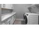 Bright laundry room featuring white cabinets, countertop, modern washer and dryer, and wood-look tile floor at 30639 N Dorado Ct, Queen Creek, AZ 85144