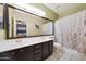 Spacious bathroom featuring a large mirror over a double sink and a shower with patterned curtain at 4210 W Rosemonte Dr, Glendale, AZ 85308
