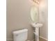 A half bathroom offering a pedestal sink, round mirror, and convenient toilet at 45071 W Portabello Rd, Maricopa, AZ 85139