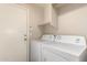Laundry room with appliances, storage shelves, and a door at 45071 W Portabello Rd, Maricopa, AZ 85139