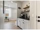 Coffee bar with floating shelves and white cabinets in entry way with bench and window at 5871 N 187Th Ln, Litchfield Park, AZ 85340