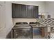Laundry room with stainless steel washer and dryer set, granite countertops and mosaic backsplash at 5940 W Robinson Way, Chandler, AZ 85226